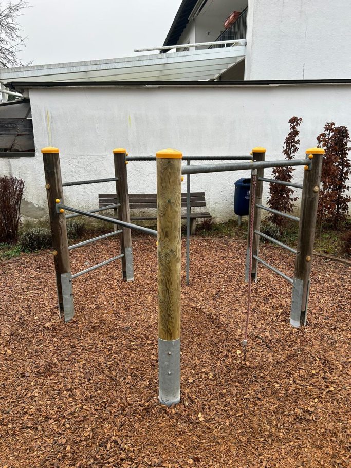 Ein Spielplatzgerät aus Metall und Holz mit mehreren Stangen zum Klettern.